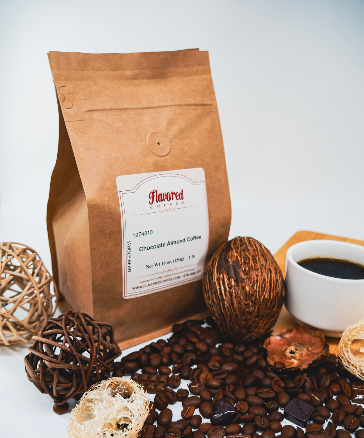Bag of Chocolate Almond Coffee next to a wooden cutting board with a white mug of coffee, coffee beans and decorative elements.