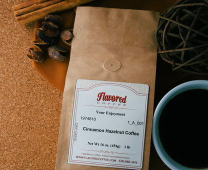 Bag of Cinnamon Hazelnut Coffee on a cork background with a cup of coffee, cinnamon sticks and decorative elements