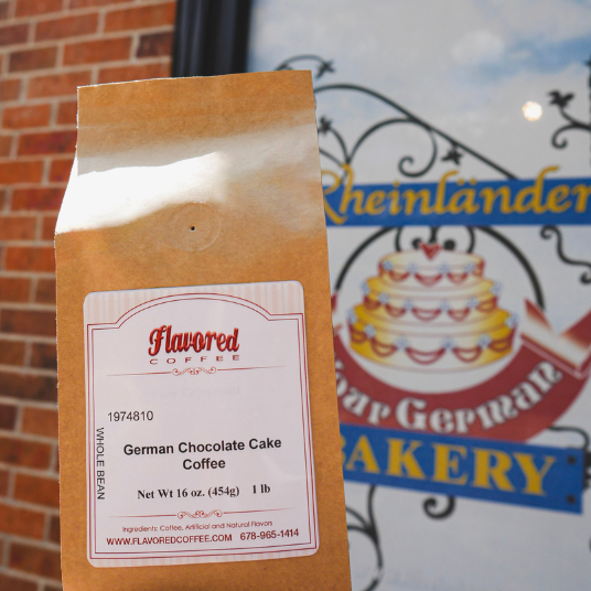 Bag of Flavored Coffee with German Chocolate Cake flavor in front of a bakery sign.