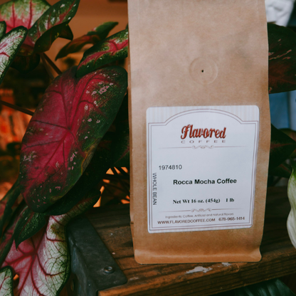 Brown coffee bag with a label on a wooden surface with plants in the background
